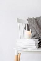 candela modello design. accogliente interno con bianca sedia, caldo plaid, libri e autunno le foglie foto