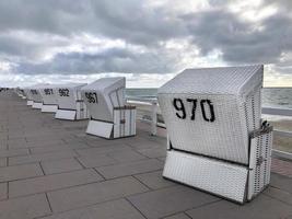 spiaggia sedie lungo il costa di silta, Germania con un' drammatico cielo al di sopra di il mare foto