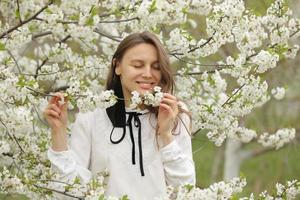 la bella ragazza felice si è tolta la maschera medica per respirare l'odore dei fiori. una ragazza con una maschera sta in fiore. la fine della quarantena foto