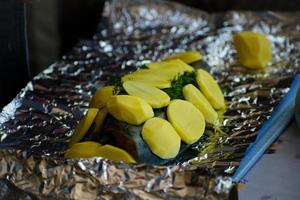 donna è cucinando salmone pesce con con patate e e aneto nel Foglio. foto