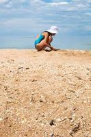 sabbia e shelly spiaggia vicino su e giocando ragazza foto