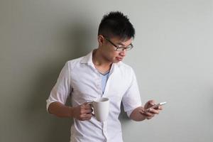Ritratto di un uomo asiatico alla moda, usando il suo telefono cellulare. foto