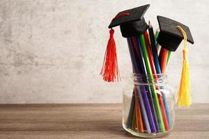 cappello di laurea con matite colorate sul libro con spazio di copia, apprendimento del concetto di istruzione universitaria. foto