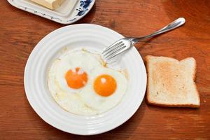 prima colazione con Due fritte uova nel bianca piatto foto