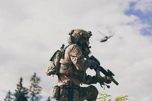 guerra concetto. un' barbuto soldato nel un' speciale forze uniforme combattente un nemico nel un' foresta la zona. selettivo messa a fuoco foto