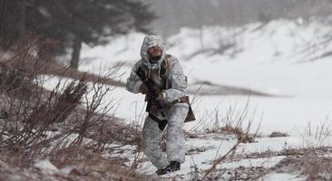 inverno guerra nel il artico montagne. operazione nel freddo condizioni.soldato nel inverno mimetizzato uniforme nel moderno guerra esercito su un' neve giorno su foresta campo di battaglia con un' fucile. selettivo messa a fuoco foto