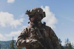 guerra concetto. un' barbuto soldato nel un' speciale forze uniforme combattente un nemico nel un' foresta la zona. selettivo messa a fuoco foto