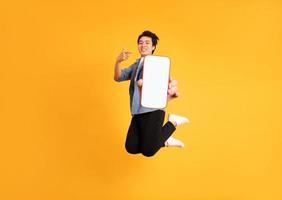 Immagine di salto su asiatico uomo Tenere smartphone nel mano, isolato su giallo sfondo foto