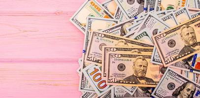 dollari su uno sfondo di legno rosa. soldi sul tavolo. dollari americani. foto