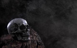 Halloween umano cranio su un vecchio di legno tavolo al di sopra di nero sfondo. forma di cranio osso per Morte testa su Halloween Festival quale mostrare orrore il male dente paura e pauroso con nebbia Fumo, copia spazio foto