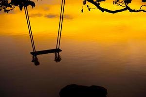 legna swing bellissimo tramonto su il mare rosa sfondo foto