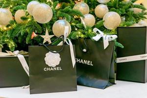 Mosca, Russia, 2021 - chanel logo su nero carta borse con regali sotto Natale albero. lussuoso marca di Abiti, Accessori e cosmetici. shopping concetto per inverno vacanze. foto