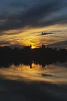 atmosferico tramonto dietro a alberi e riflessione nel acqua. foto