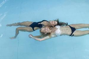 donne nel piscina acqua. bellissimo contento donne con sexy in forma corpo rilassante, galleggiante nel nuoto piscina a terme Hotel. estate vacanze vacanza. salutare stile di vita. benessere, bellezza, Salute concetto foto