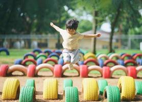 carino asiatico ragazza Sorridi giocare salto su scuola scuola materna cortile o terreno di gioco. salutare estate attività per bambini. poco asiatico ragazza arrampicata all'aperto a terreno di gioco. bambino giocando a terreno di gioco. foto