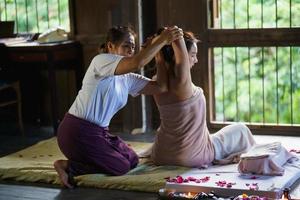 massaggio e spa trattamento rilassante della sindrome dell'ufficio tradizionale stile di massaggio tailandese. asain massaggiatrice femminile che fa massaggi cura mal di schiena, dolore alle braccia e stress per la donna dell'ufficio stanca dal lavoro. foto