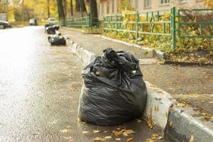 Borsa di spazzatura su lato di strada. foglia raccolta. raccolta rifiuto nel nero Borsa. foto