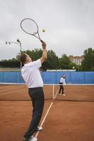 Novelli sposi giocare tennis su il Tribunale simboleggiante famiglia relazioni foto