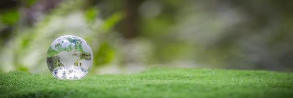 globo pianeta bicchiere nel verde foresta con bokeh natura luci. mondo ambiente giorno. concetto di ambiente conservazione, proteggere ecologia terra e ambientale eco-friendly vita bandiera e copia spazio foto