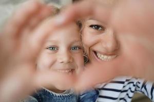 poco figlia e amorevole mamma rendere autoscatto con cuore mano gesto insieme. adozione, bambino cura foto