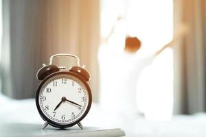 uomo odia veglia su presto nel il mattina. assonnato ragazza guardare a allarme orologio e provando per nascondere sotto il cuscino foto