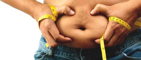 Grasso uomo dai un'occhiata su corpo sovrappeso addome il suo pancia con nel mano misurazione nastro foto