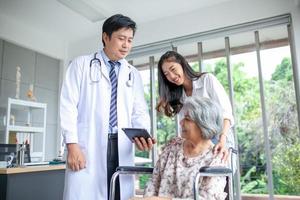 asiatico medico spiegando malattia per anziano paziente con tavoletta sorridente nel comfort a casa, assistenza sanitaria e medicina concetto. foto