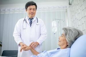 asiatico medico supporto e applauso su anziano paziente nel Ospedale, parlando sorridente nel comfort. assistenza sanitaria e medicina concetto. foto