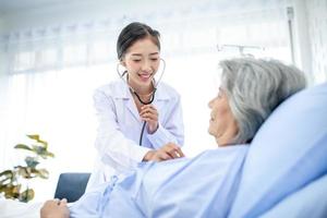 bellissimo asiatico medico con stetoscopio e documento cartella, esaminare il sintomo per paziente nel il recupero camera. assistenza sanitaria e medicina concetto. foto