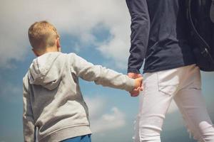 posteriore Visualizza di figlio Tenere Il padre di mano contro il cielo. foto