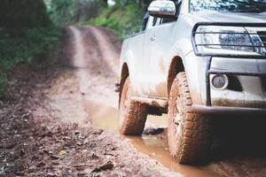 auto fuoristrada sporca, suv coperto di fango su strada di campagna, pneumatici fuoristrada, viaggi fuoristrada e concetto di guida. foto