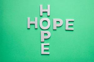 speranza parola con di legno lettere su il verde sfondo foto