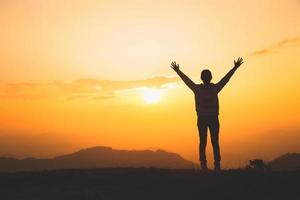 l'uomo alza la mano in cima alla montagna e al tramonto, la libertà e il concetto di avventura di viaggio. credenze religiose, copia spazio. foto