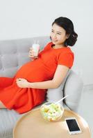 giovane incinta donna avendo prima colazione con insalata e latte. foto