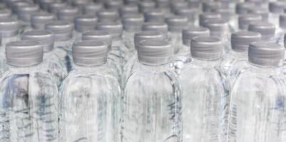 un' grande numero di plastica in bottiglia acqua prodotti nel un' potabile acqua pianta quello siamo disposte nel un' riga in attesa per essere venduto per supermercati. bevanda e potabile acqua attività commerciale. foto