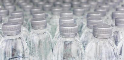 un' grande numero di plastica in bottiglia acqua prodotti nel un' potabile acqua pianta quello siamo disposte nel un' riga in attesa per essere venduto per supermercati. bevanda e potabile acqua attività commerciale. foto