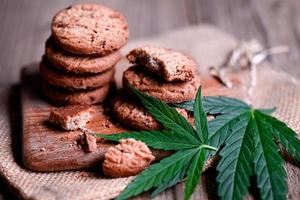 delizioso dolce dolce biscotto con canapa foglia pianta THC CBD erbe aromatiche cibo merenda e medico, canapa cibo biscotti con torta cioccolato canapa foglia marijuana erba su di legno sfondo foto