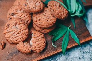 delizioso dolce dolce biscotto con canapa foglia pianta THC CBD erbe aromatiche cibo merenda e medico, canapa cibo biscotti con torta cioccolato canapa foglia marijuana erba su di legno sfondo foto