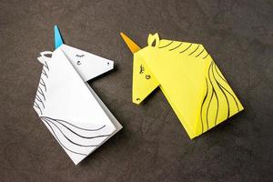 unicorni bianchi e gialli realizzati con la tecnica dell'origami su sfondo nero. foto