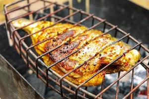 grigliato pesce su il griglia, cucinato su fuoco, barbecue foto