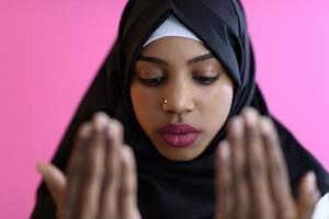 moderno africano musulmano donna fa tradizionale preghiera per Dio, mantiene mani nel preghiere gesto, indossa tradizionale bianca Abiti foto