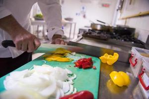 mani dello chef che tagliano verdure fresche e deliziose foto