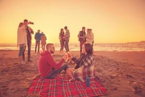 coppia godendo con amici a tramonto su il spiaggia foto