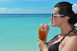 bellissimo giovane donna con un' bevanda di il mare foto