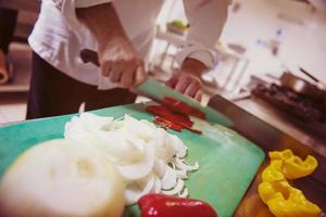 mani dello chef che tagliano verdure fresche e deliziose foto