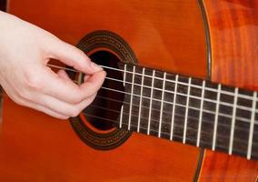 femmina braccio giochi su acustico chitarra foto