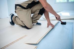 lavoratore professionista che installa un nuovo pavimento in legno laminato foto