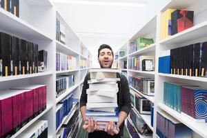 alunno Tenere lotto di libri nel scuola biblioteca foto