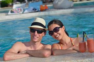 contento giovane coppia rilassare e prendere fresco bevanda su bordo piscina foto
