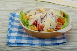 Cesare insalata con pollo nel un' ciotola su di legno sfondo foto